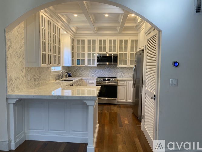 A kitchen with white cabinets and a marble countertop.