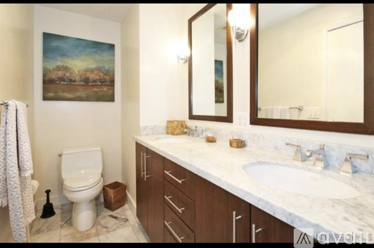 A bathroom with a toilet, sink, and a painting on the wall.
