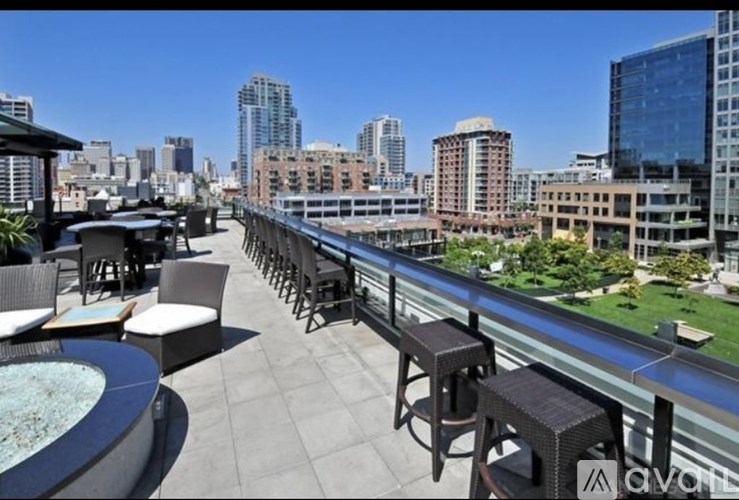 A rooftop patio with a hot tub and chairs overlooking a city skyline.