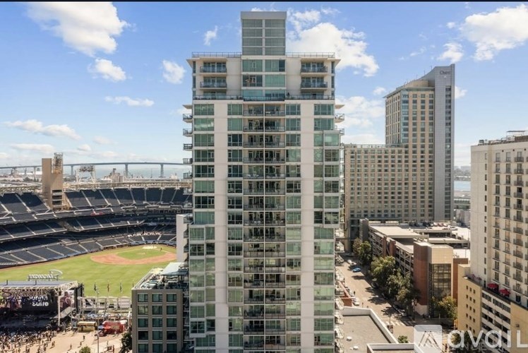 A tall building with many windows is in the foreground of a stadium.
