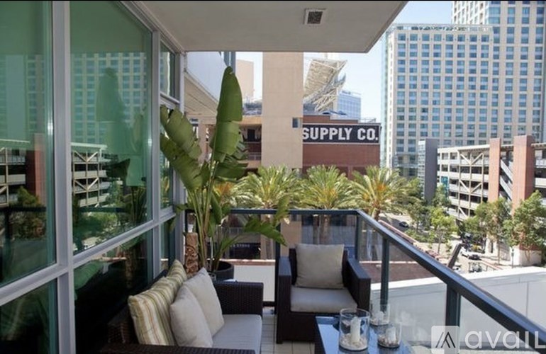 A patio with a couch and a table with a glass of water on it.