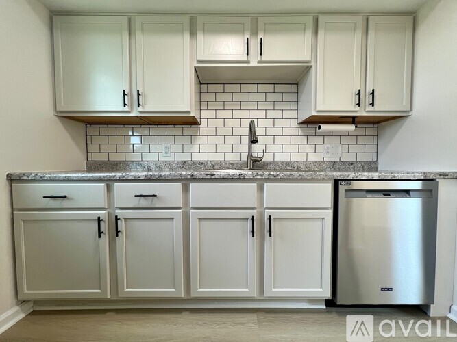 A kitchen with white cabinets and a marble countertop.