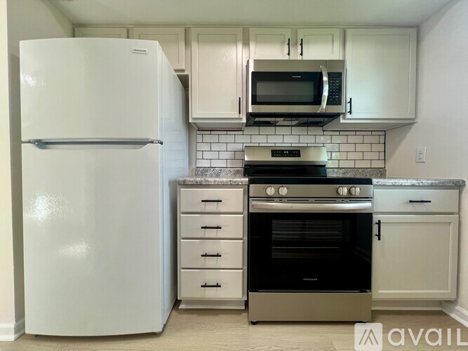 A white refrigerator stands next to a white oven in a kitchen.