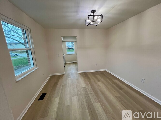 A room with wooden flooring and a window overlooking a street.