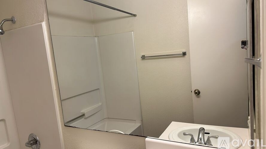 A white bathroom with a sink and a shower stall.