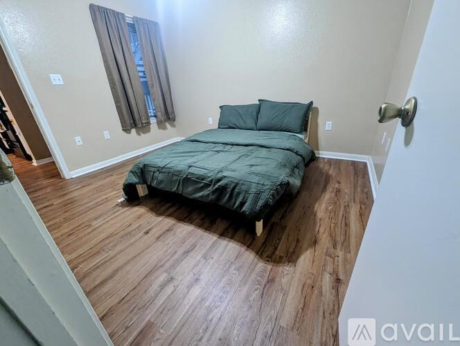 A bedroom with a bed covered in a green blanket.