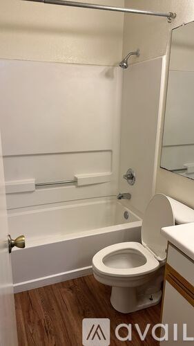 A white toilet in a small bathroom with a white tub and a white door.
