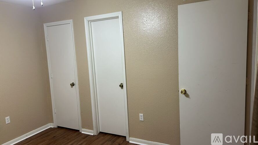 Three white doors are in a hallway.