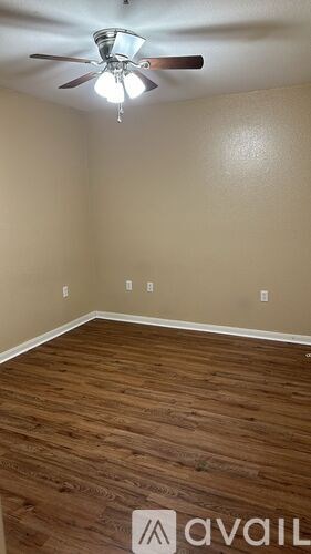 A room with a ceiling fan and wooden flooring.
