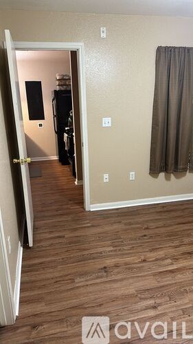 A room with a door open to another room with a brown curtain.