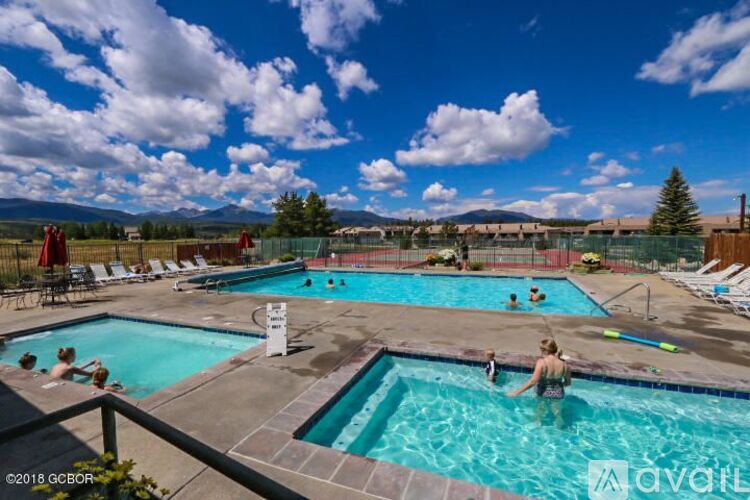 A sunny day at the outdoor pool with people swimming and relaxing.
