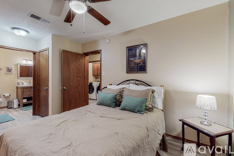 A bedroom with a bed, a ceiling fan, and a nightstand with a lamp.