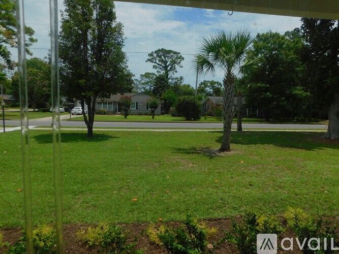 A grassy area with trees and houses in the background.