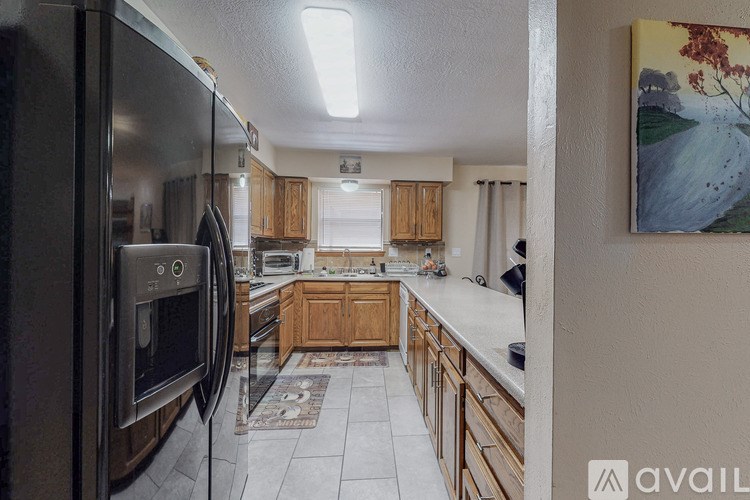 A kitchen with wooden cabinets and a black refrigerator.
