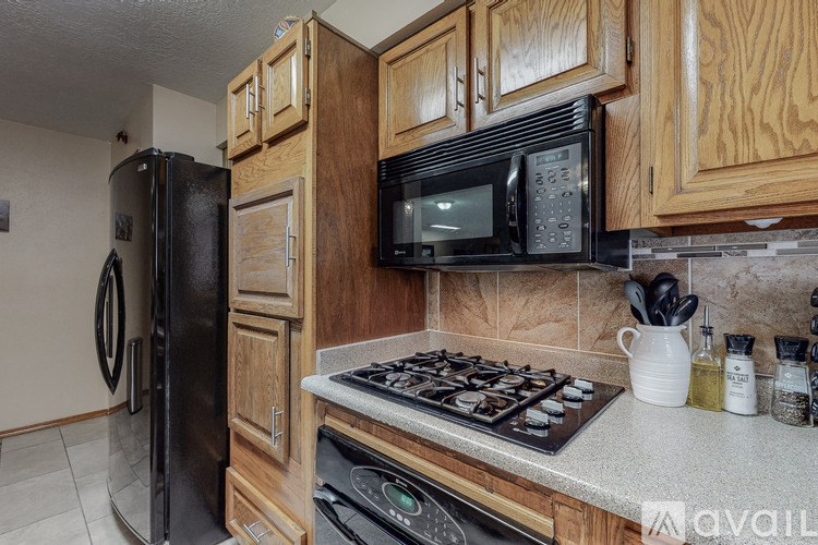 A kitchen with a black refrigerator, black microwave, and a stove top oven.