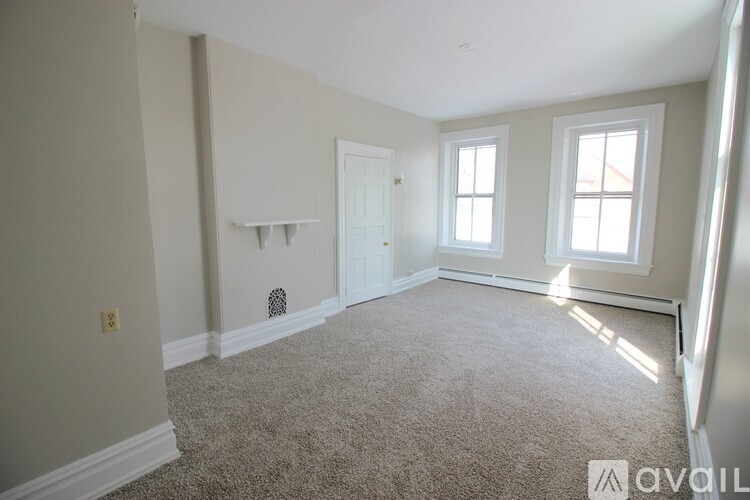 A room with a carpeted floor and three windows.