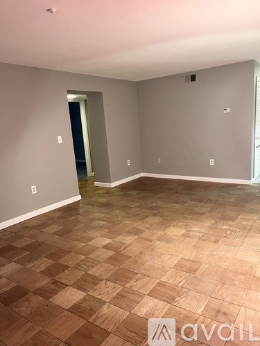 A room with wooden flooring and a doorway leading to another room.