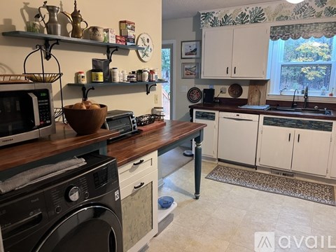 A kitchen with a washing machine and a microwave on the counter.