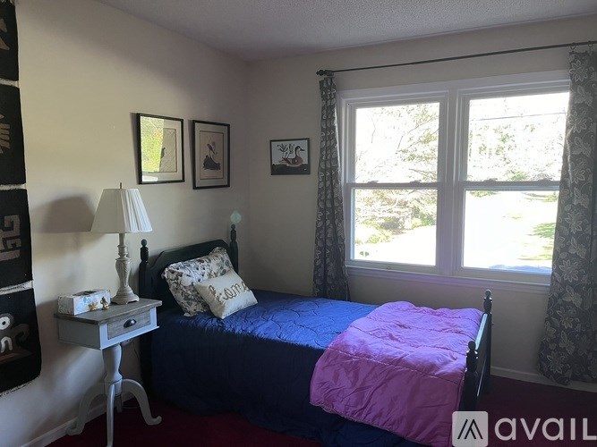 A bedroom with a bed, nightstand, and window.