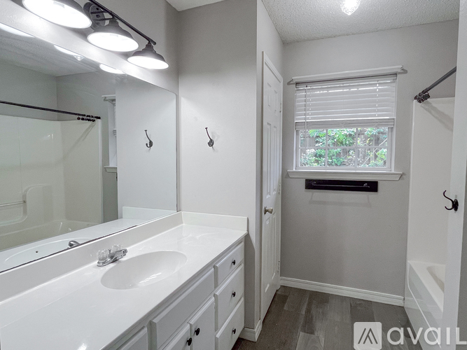 A bathroom with a sink, mirror, and a window.