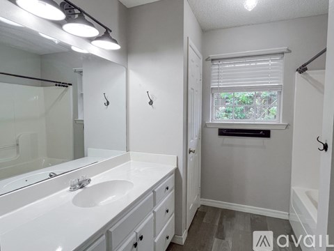 A bathroom with a sink, mirror, and a window.