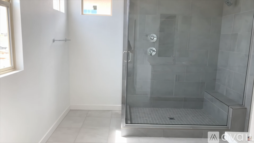 A glass shower door is open to a tiled shower.