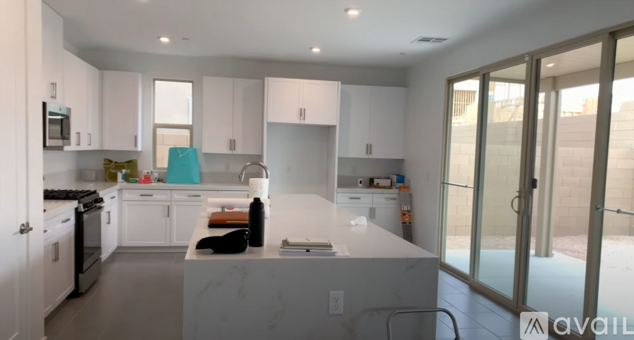 A modern kitchen with white cabinets and a marble island.