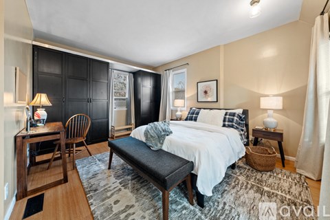 A bedroom with a bed, chair, and a table with a lamp on it.