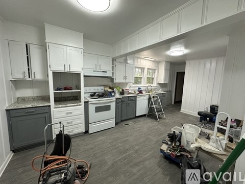 A kitchen under renovation with white cabinets and a grey island.