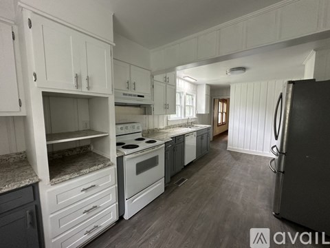 A kitchen with grey cabinets and a black stool.