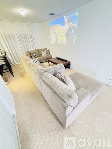 A living room with a large couch and a flat screen TV mounted on the wall.