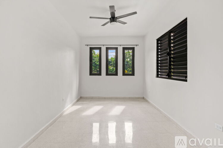 A room with a ceiling fan and a window with blinds.
