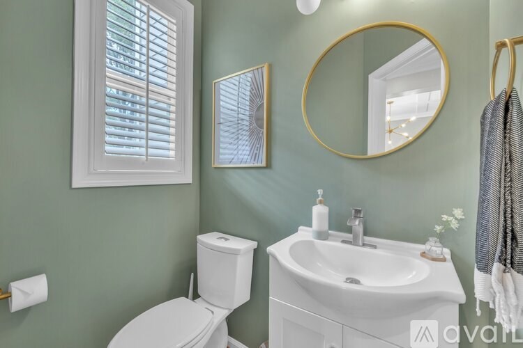 A bathroom with a toilet, sink, and mirror.