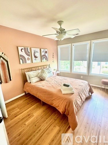 A bedroom with a bed, a ceiling fan, and a window.