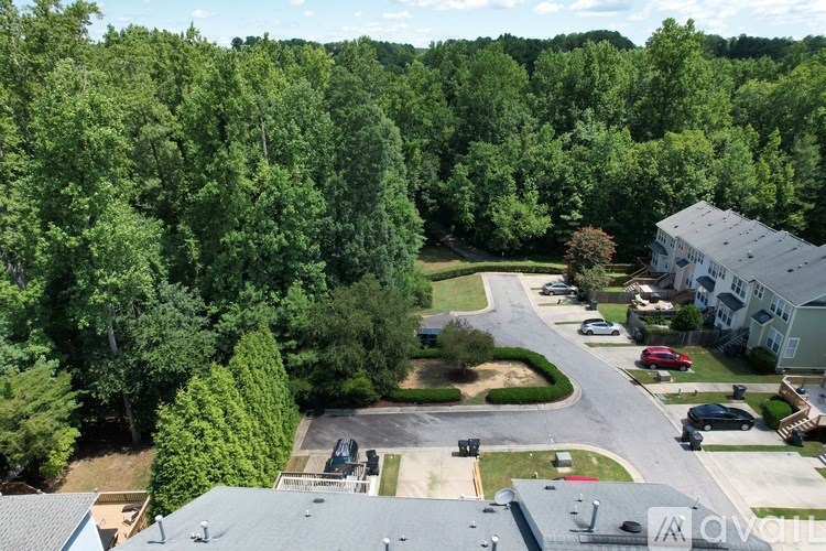 A bird's eye view of a residential area with houses, cars, and trees.