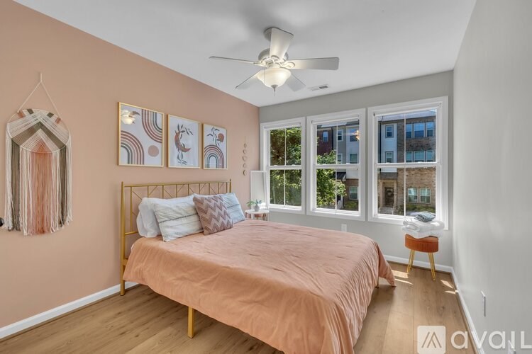 A bedroom with a bed, a ceiling fan, and a window with a view of a building outside.