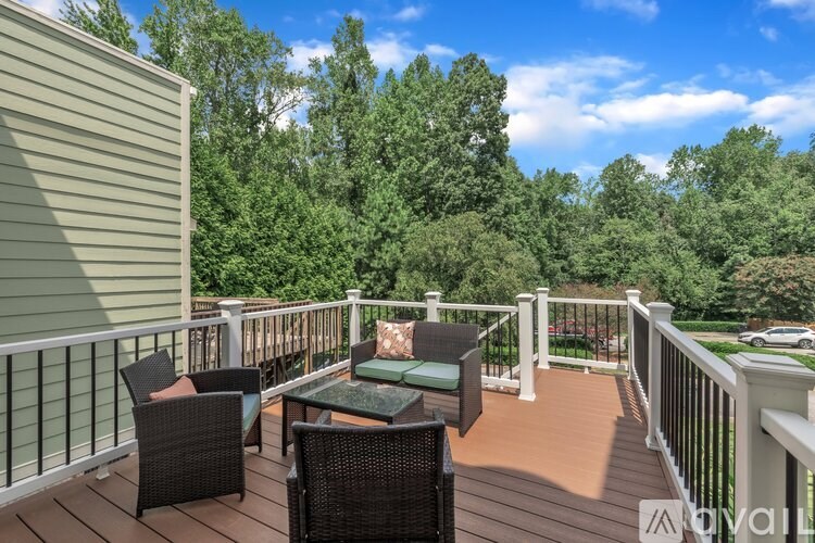 A patio with a table and chairs overlooking a wooded area.