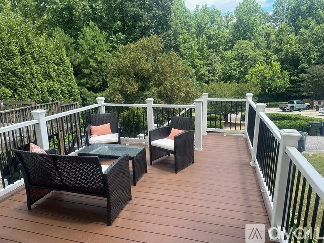 A wooden deck with a table and chairs overlooking a wooded area.