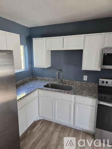 A kitchen with white cabinets and a granite countertop.