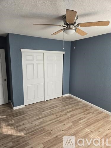 A room with a ceiling fan and a white door.