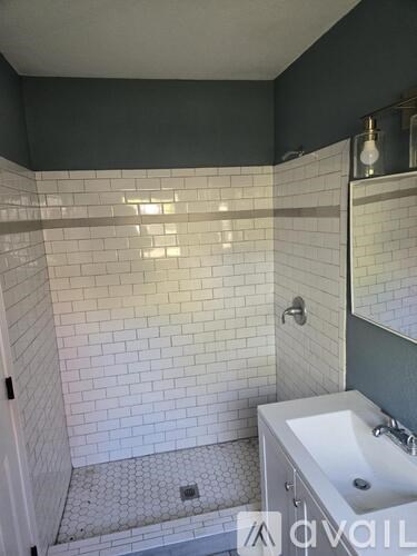 A white sink in a bathroom with a white tiled shower.