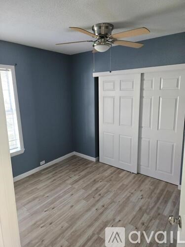 A room with a ceiling fan and a white door.