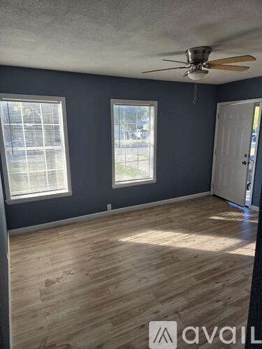 A room with a ceiling fan and two windows.