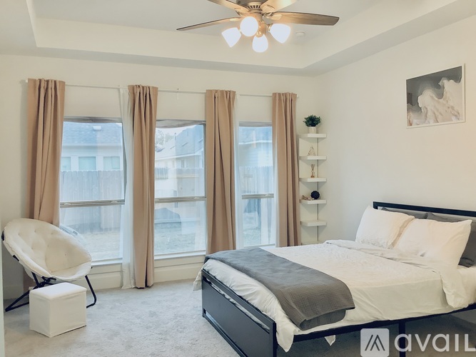 A bedroom with a large bed, a chair, and a ceiling fan.