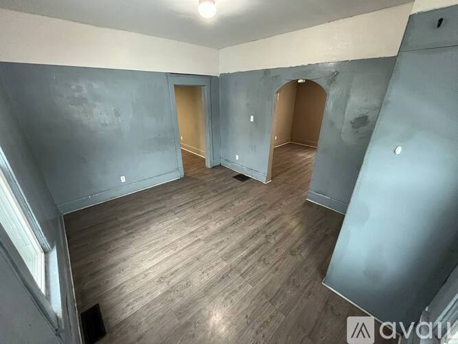 A room with wooden flooring and two open doors.