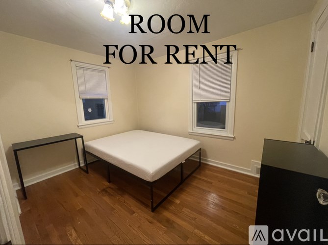 A room for rent with a bed, a desk, and a window.