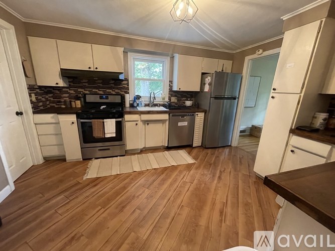 A kitchen with wooden floors and a stone backsplash.