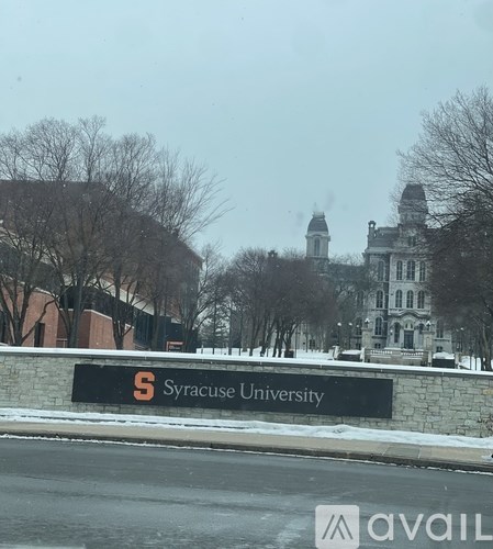 A sign for Syracuse University is in front of a building.