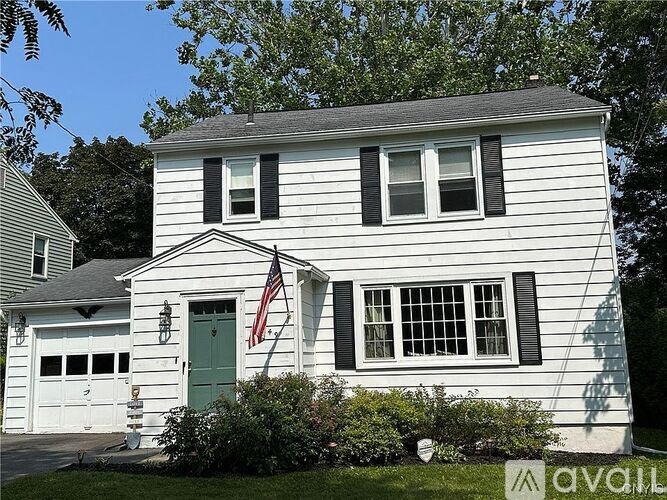 A white house with a green door and an American flag on the front.