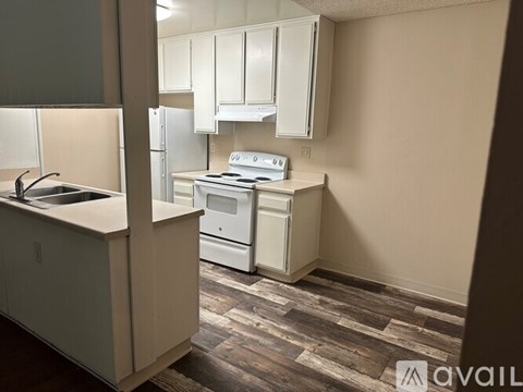 A kitchen with a stove, sink, and cabinets.